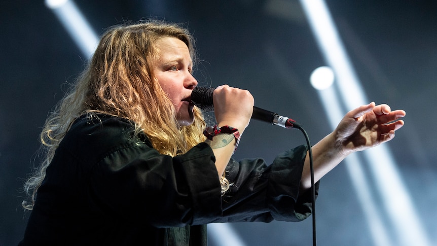 Kae Tempest raps into a microphone and motions to the crowd on stage at Primavera Sound 