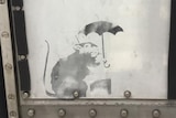 A spray-painted image of a rat holding an umbrella.