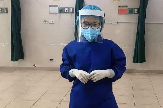 A young woman in glasses, face shield and mask and scrubs