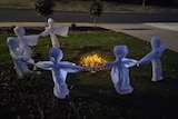 Ghosts made of white fabric standing around a campfire in a front garden