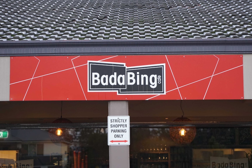 A tight shot of shopfront signage outside Bada Bing cafe with the cafe's black logo on a large red sign.