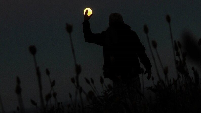 Silhouette of man against giant yellow moon