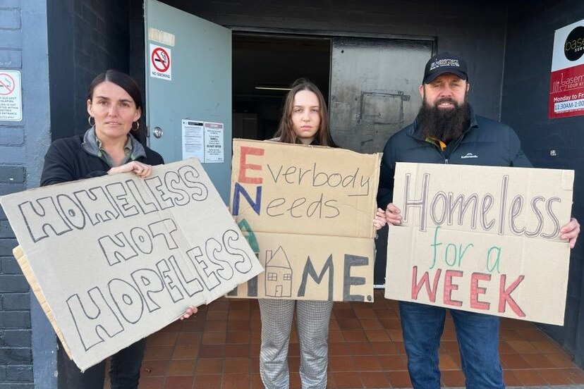 Three people, two women and a man hold signs that say homeless not helpless