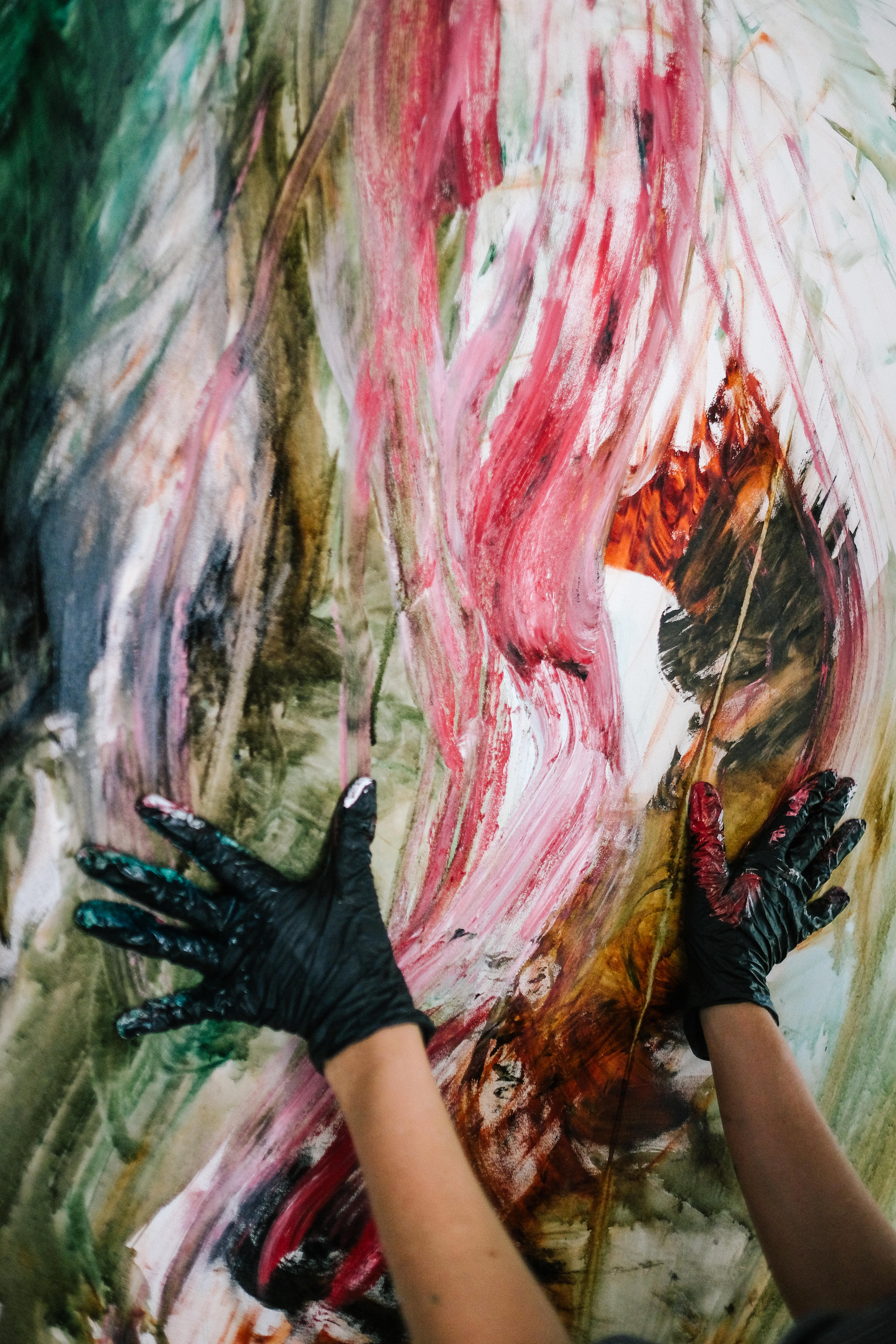 Close up of Walker’s hands on the canvas - she wears black gloves and drags her paint coloured hands, creating dramatic lines. 