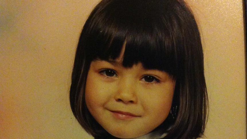 A little girl with a bob haircut and fringe sits for a portrait photo