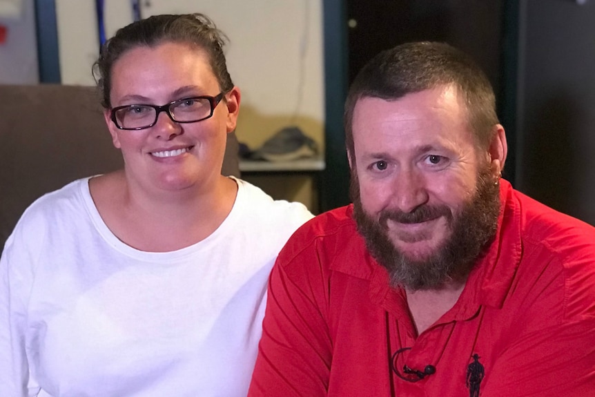 A woman wearing a white t-shirt sits next to a man in a red t-shirt