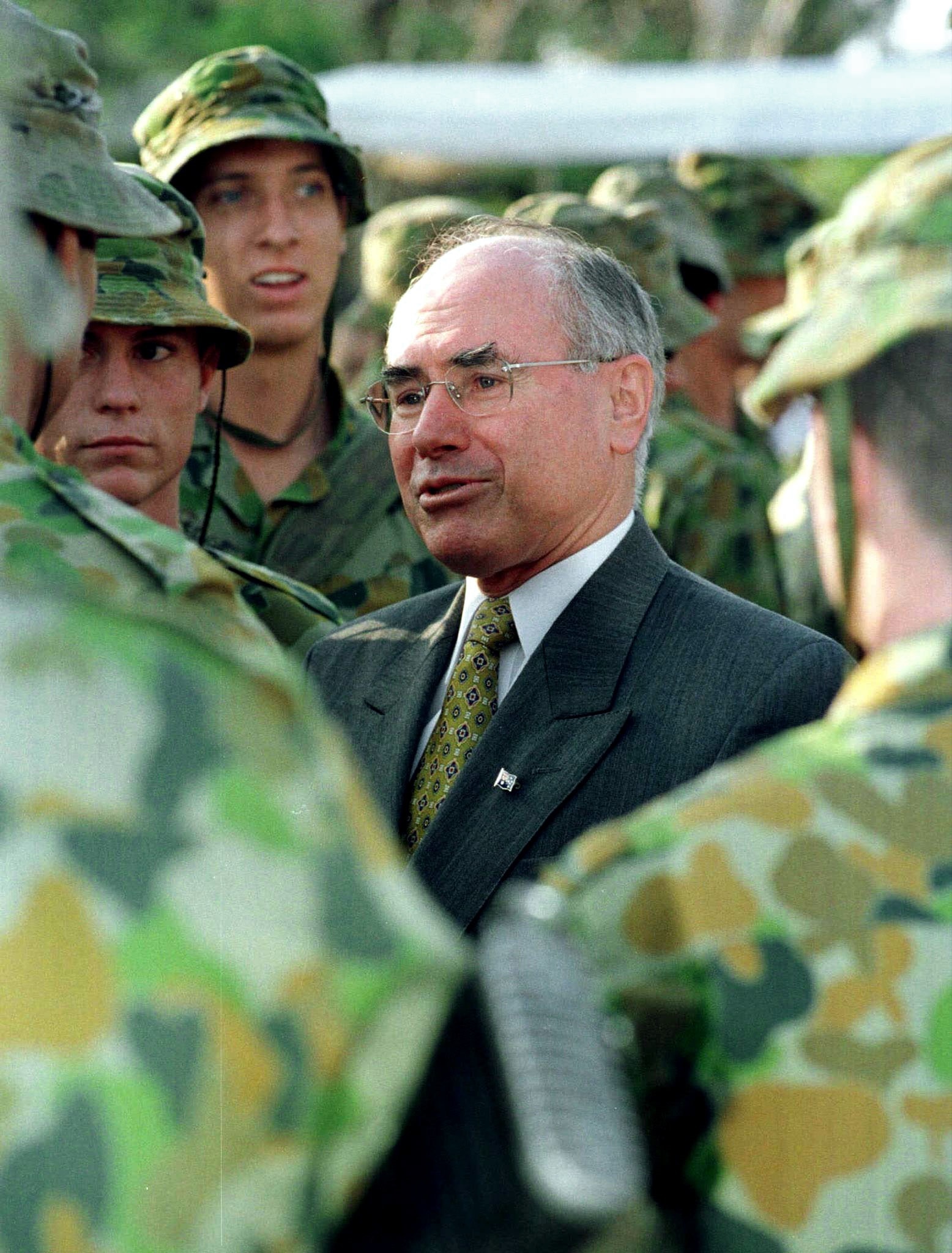 John Howard talks to a group of people in green army uniforms