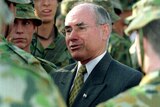 John Howard talks to a group of people in green army uniforms