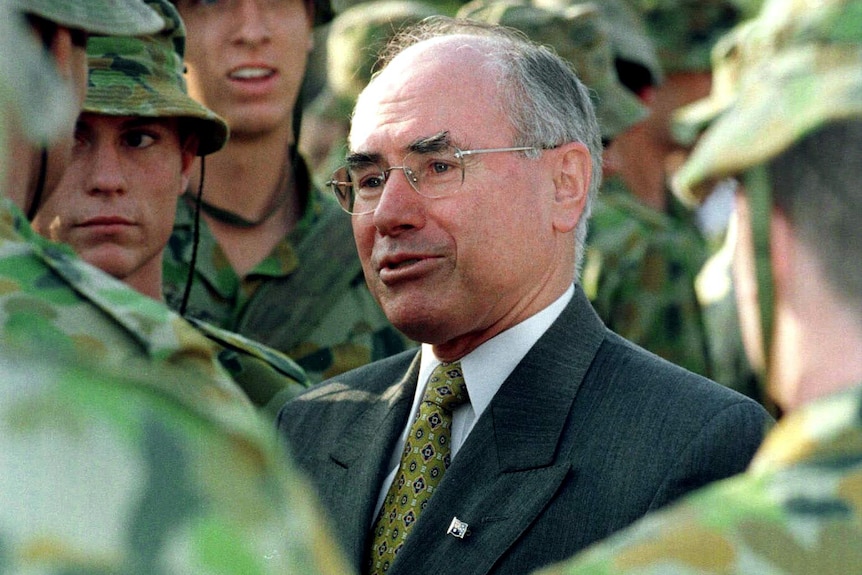 John Howard talks to a group of people in green army uniforms
