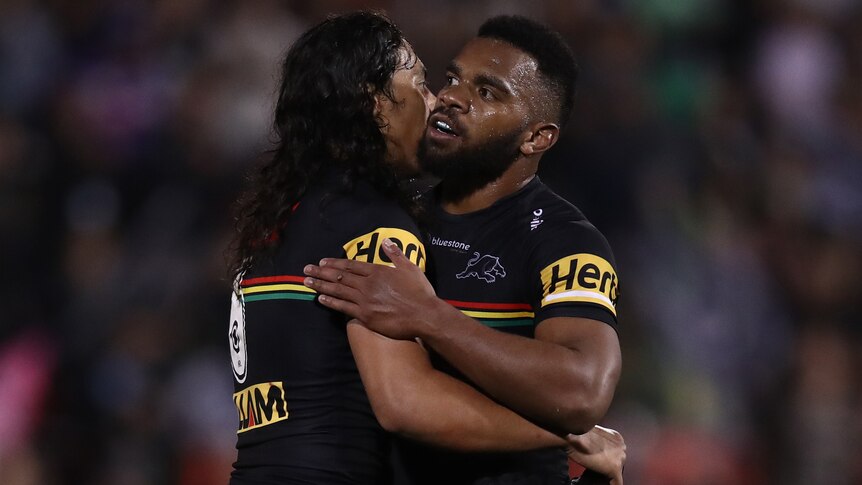 Two Penrith Panthers NRL players embrace as they celebrate a win over the Melbourne Storm.
