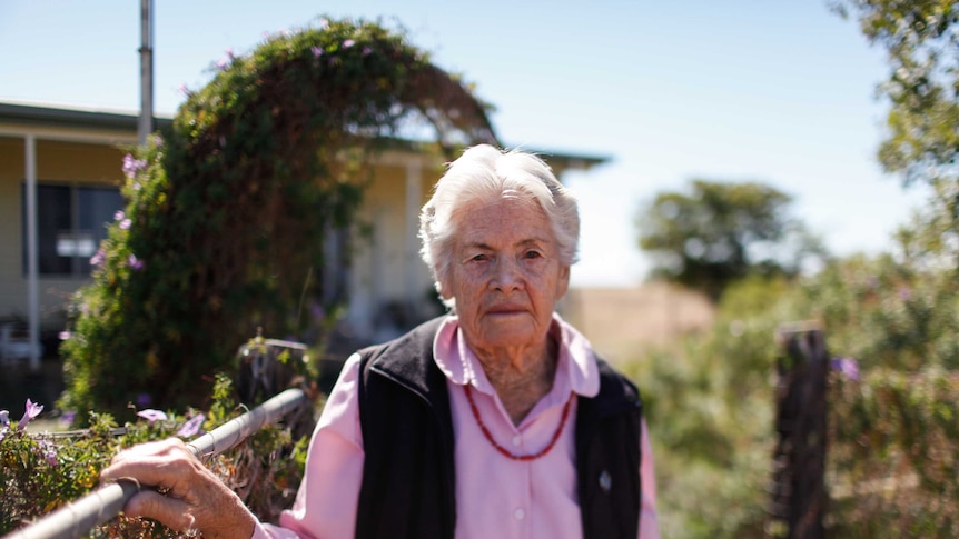 Rosie Archer looks directly into the camera in her garden, in front of her house.