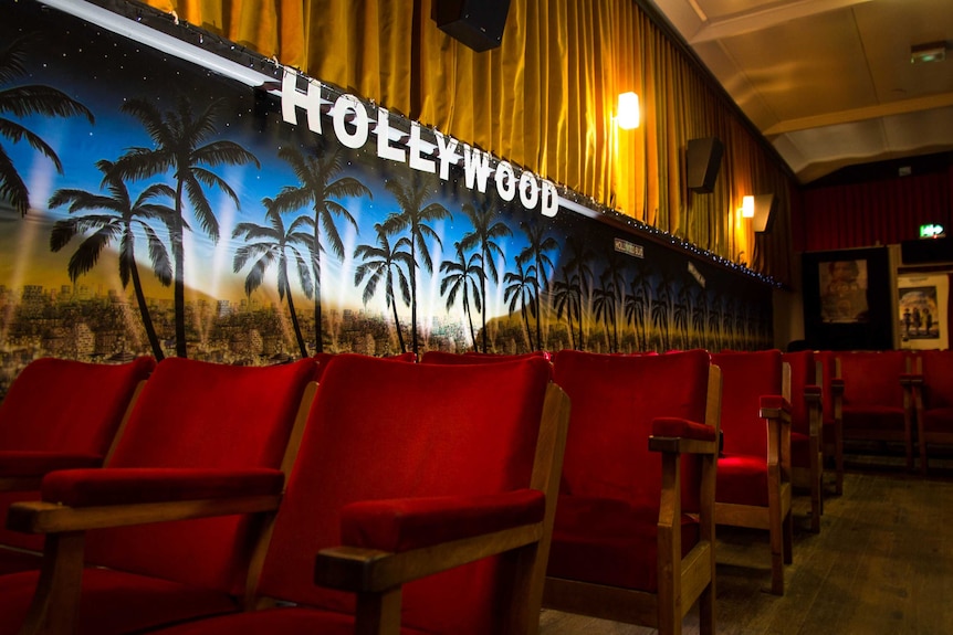 Red cinema seats sit into of a paper Hollywood sign.