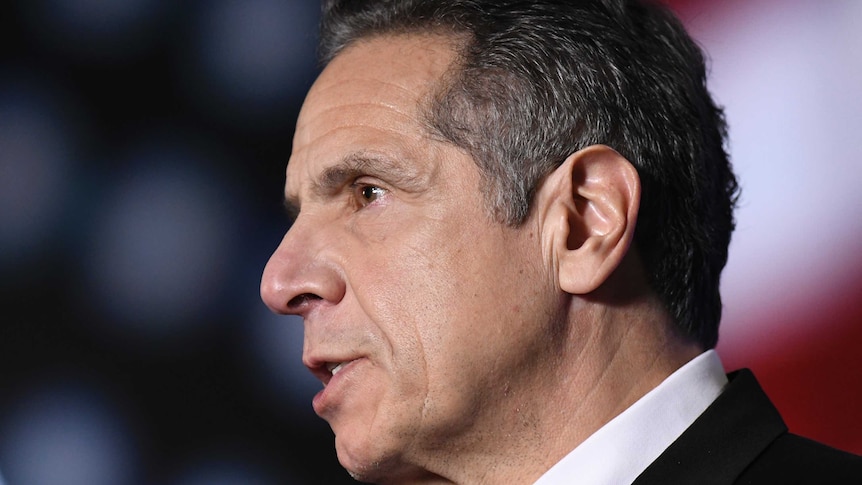 Andrew Cuomo in profile in front of a US flag