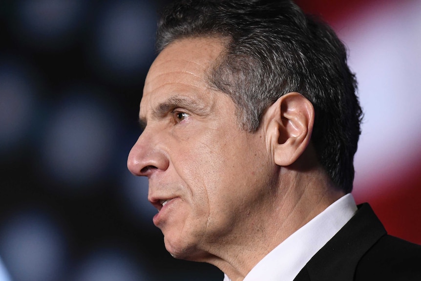 Andrew Cuomo in profile in front of a US flag