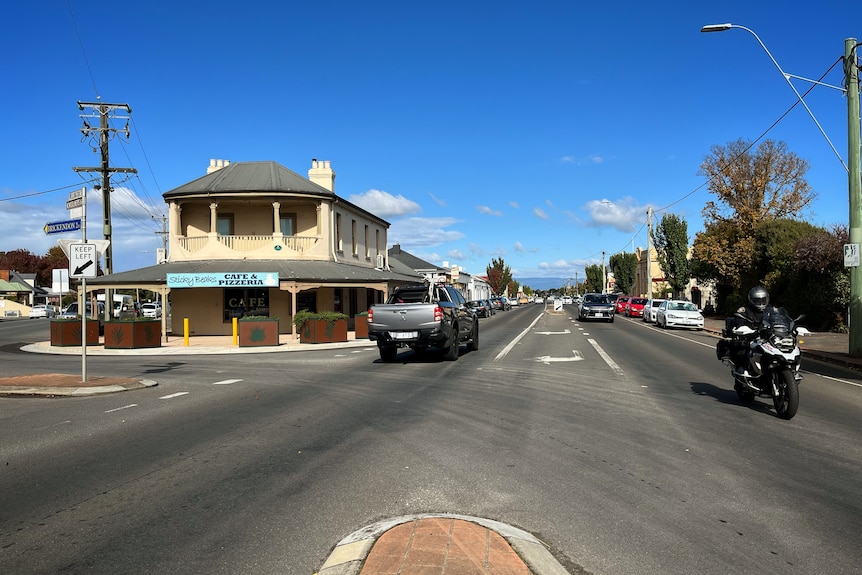 Main street of a small town in northern Tasmania with pub on the left and a motorbike driving down the road 