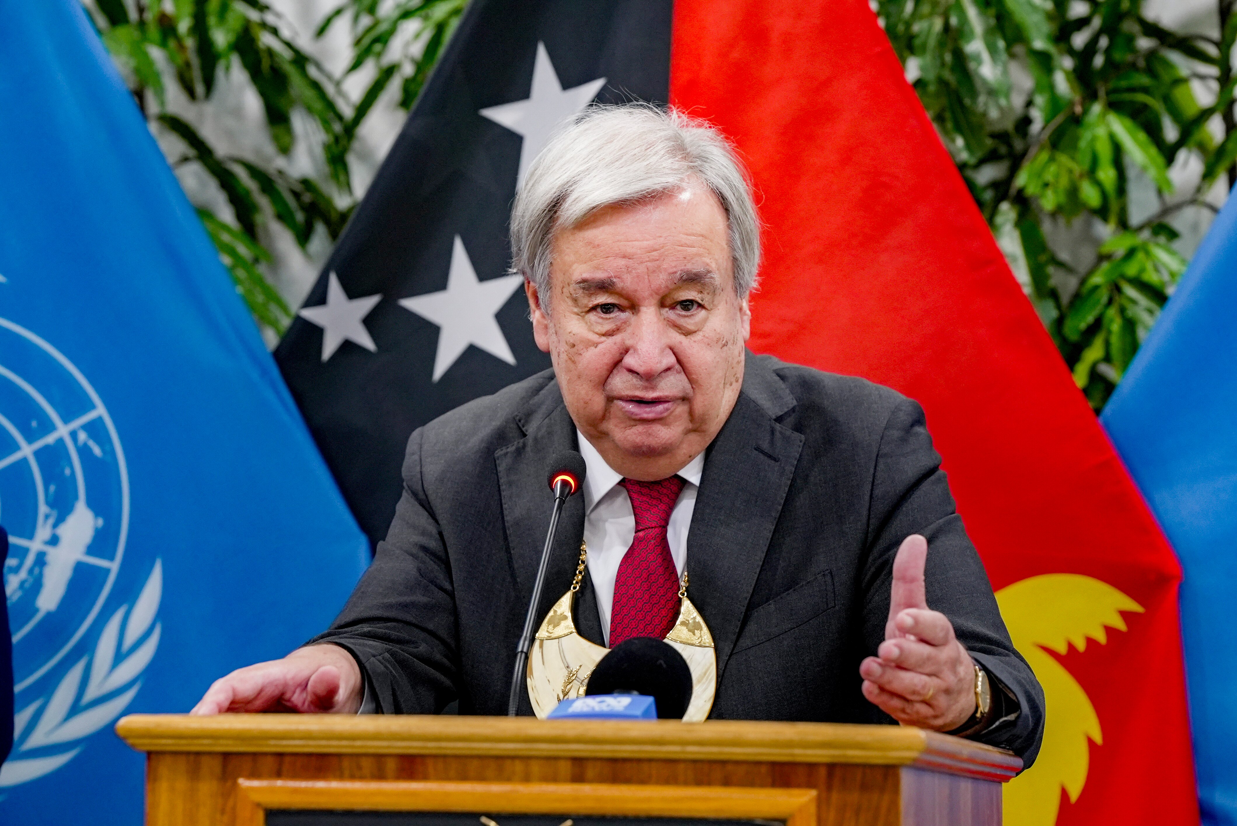 Antonio Guterres speaks in front of the PNG flag.