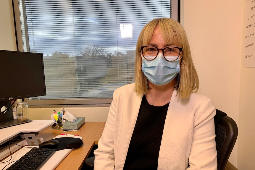 Annaliese van Diemen wears a face mask and sits at a desk