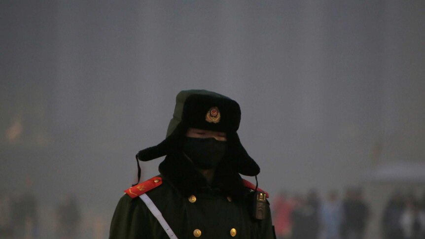 A paramilitary police officer wearing a mask is pictured in the smog at Tiananmen Square
