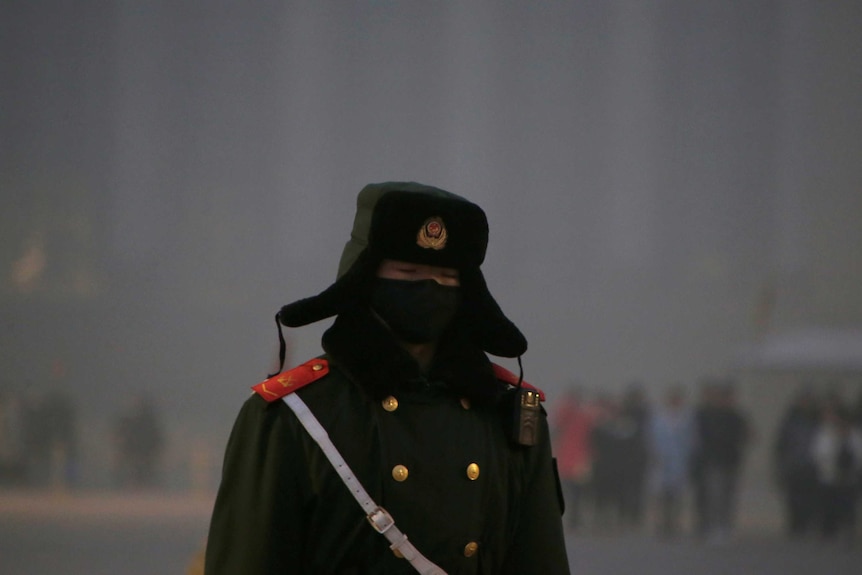 A paramilitary police officer wearing a mask is pictured in the smog at Tiananmen Square