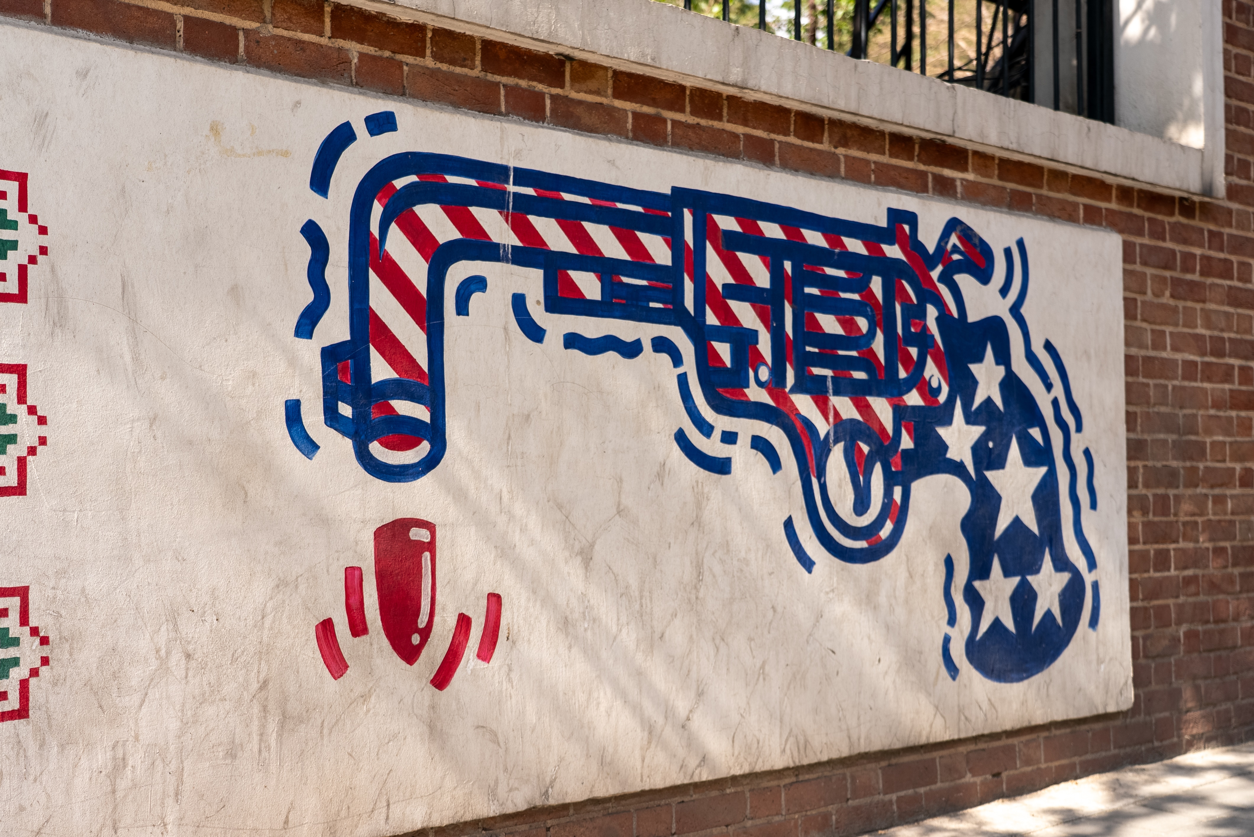 An illustration of a gun painted in the colours of the US flag - blue, red and white - on the side of a wall.