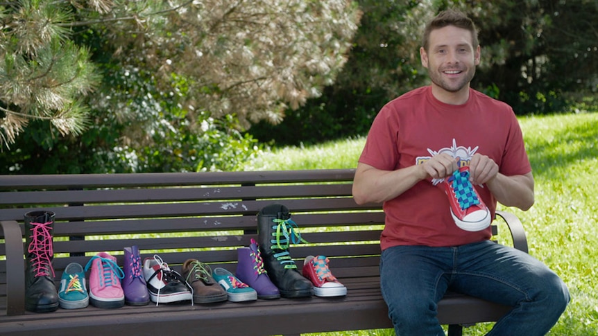 Man sits beside row of sneakers on park bench