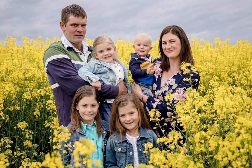 Bianca Schultz stands with her partner, three daughters and son in a field of canola.