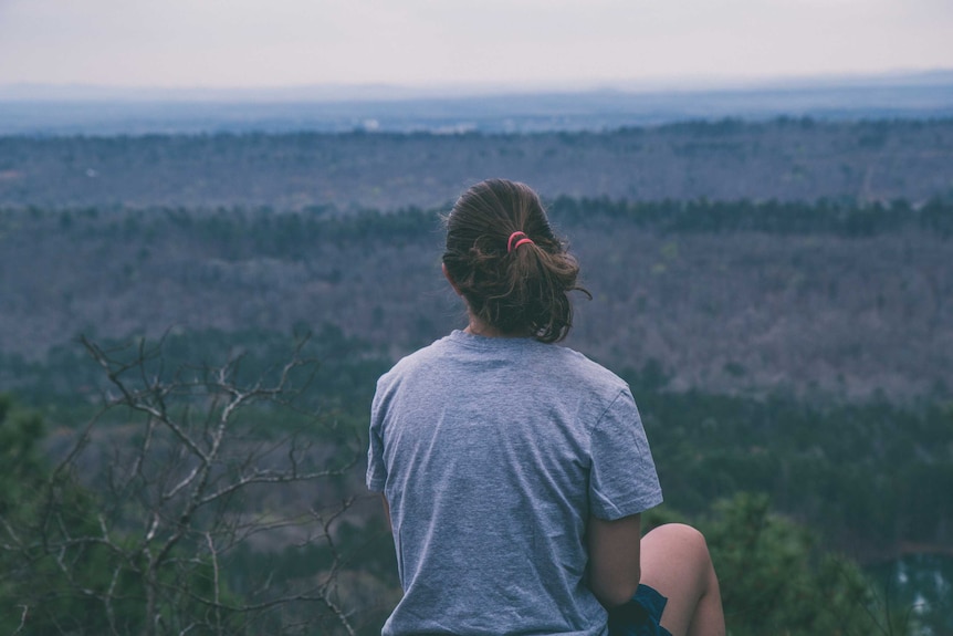 Woman looks out onto bushland.