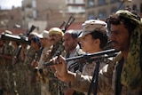 Houthi rebel fighters hold up their weapons as they stand in a row.