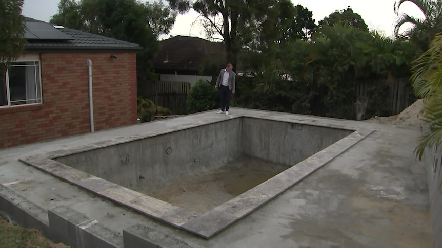 A man standing by an empty pool.