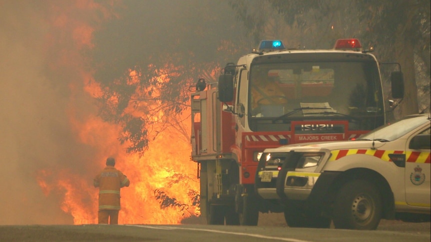 Firefighter walks towards wild flames at the Carwoola fire ground.