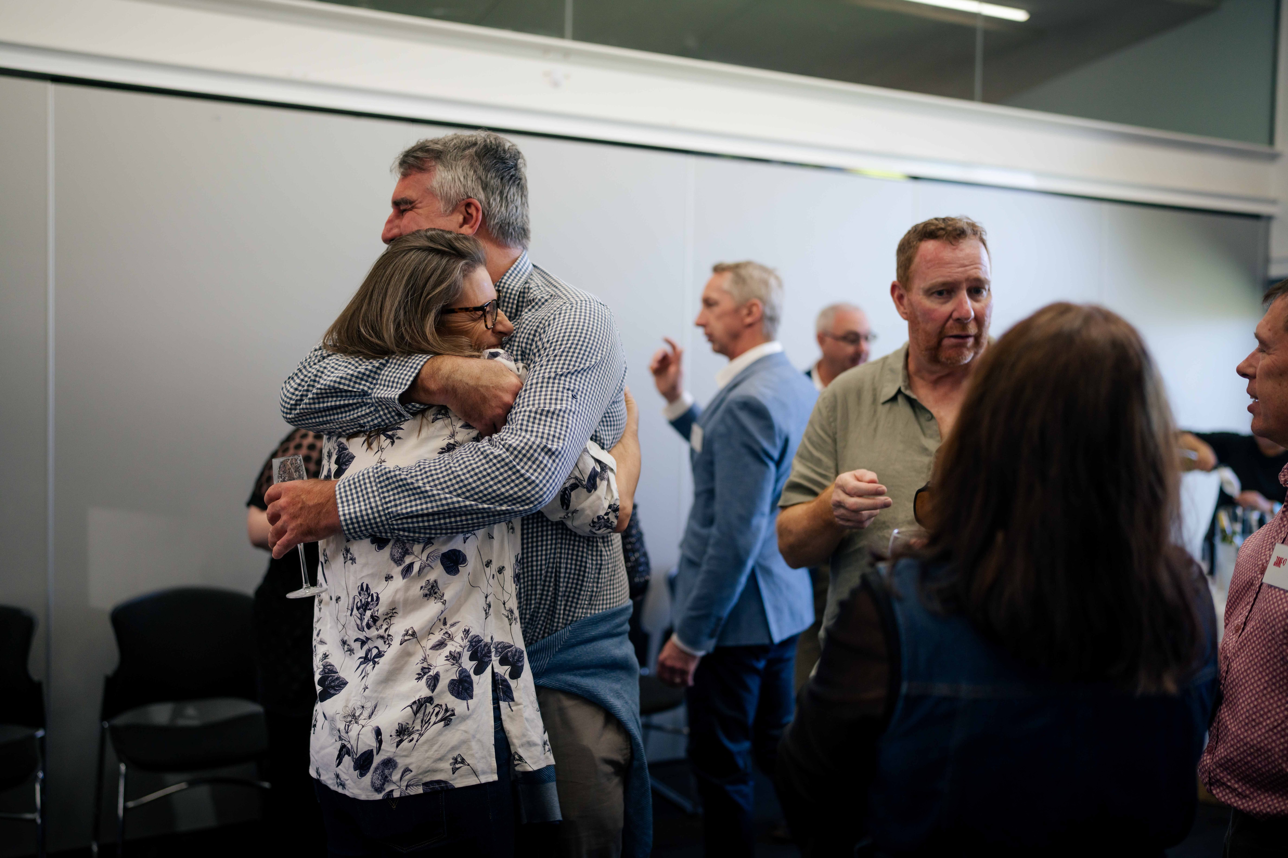 People gathered at a cocktail party, laughing, eating, drinking, chatting