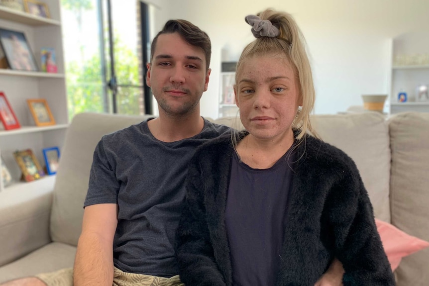 A young man and woman sitting together on a couch in a living room