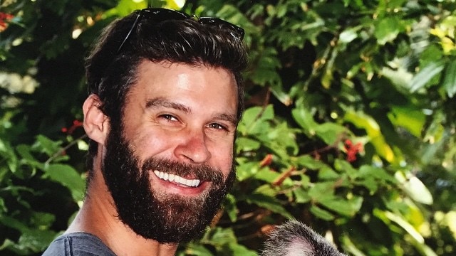 Ryan Martin smiling holding a koala