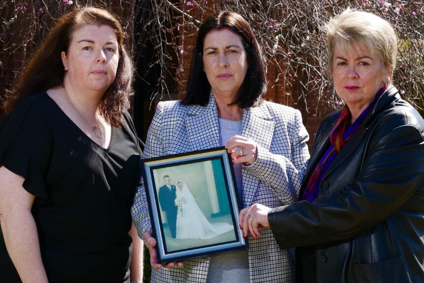 Three woman hold a picture frame