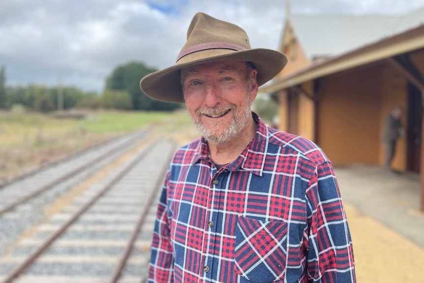 A man standing on the platform of a heritage railway station.