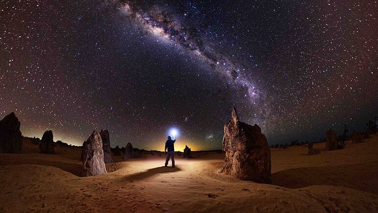 Figure standing in the desert under stars