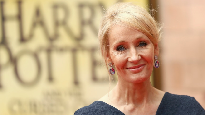 Author JK Rowling in front of a yellow Harry Potter poster at a gala performance in London.