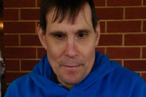 A man in a blue hoodie looking down from the camera.