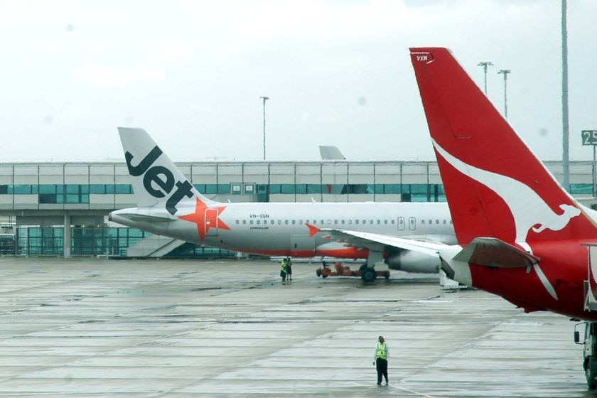 A Qantas jet and a Jetstar jet sit on the tarmac at Melbourne Airport.