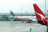 A Qantas jet and a Jetstar jet sit on the tarmac at Melbourne Airport