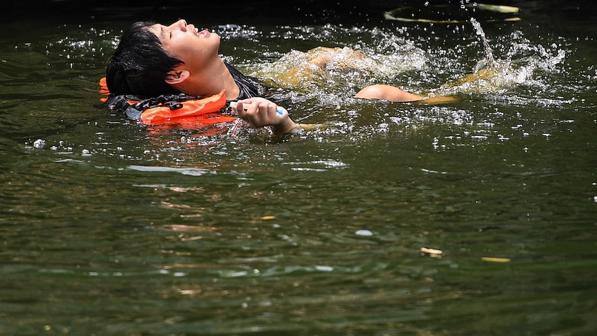 A man swims in a canal during hot weather in Bangkok.