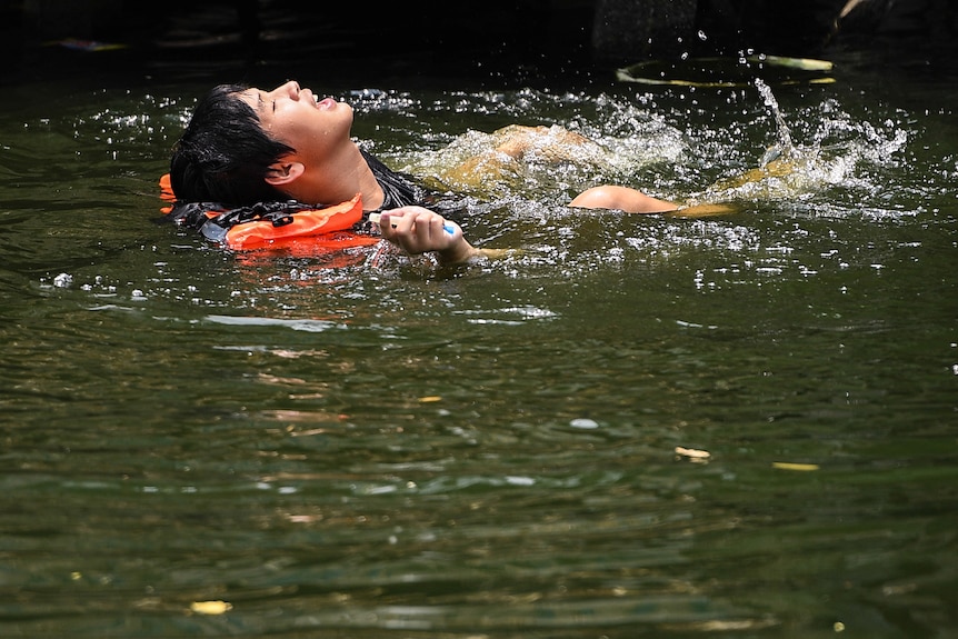 A man swims in a canal during hot weather in Bangkok.