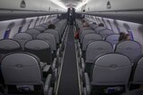 Only a few passengers are seated in a near-empty airliner cabin.