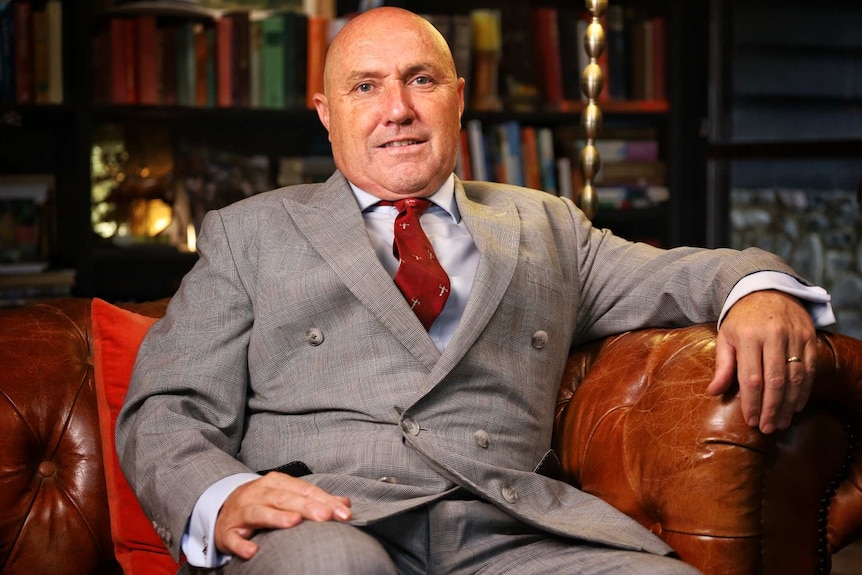 A man in a suit sits in a home library.