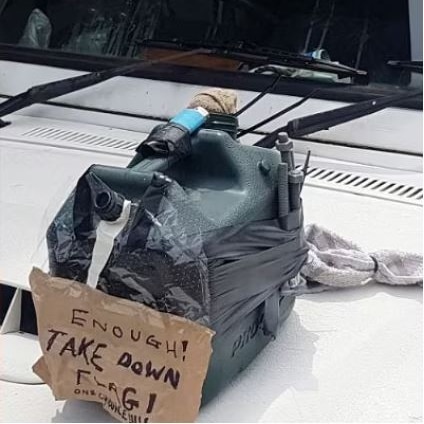 An item that appears to be a fake bomb with a note taped to the side that's been attached to the bonnet of a ute.