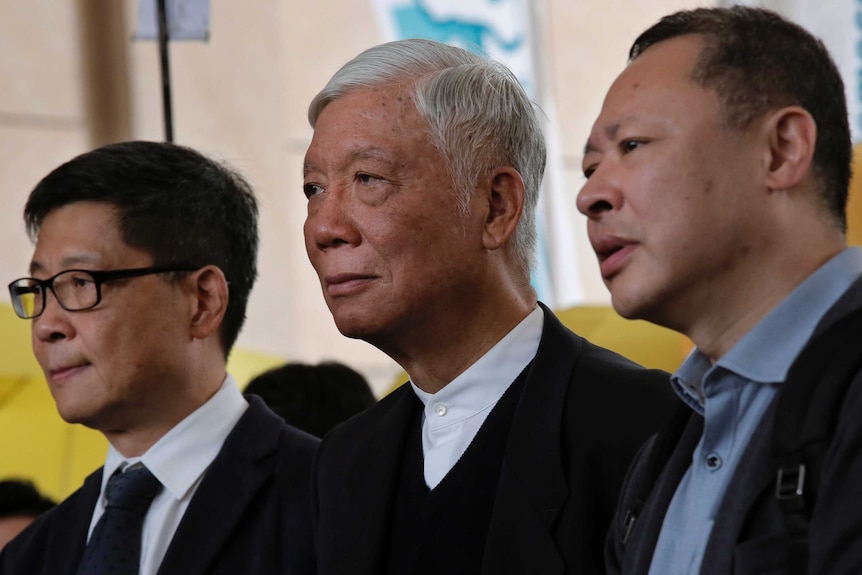 Benny Tai, wearing black rimmed glasses, Chu Yiu-ming, with white hair, and Chan Kin-man look off into the distance.