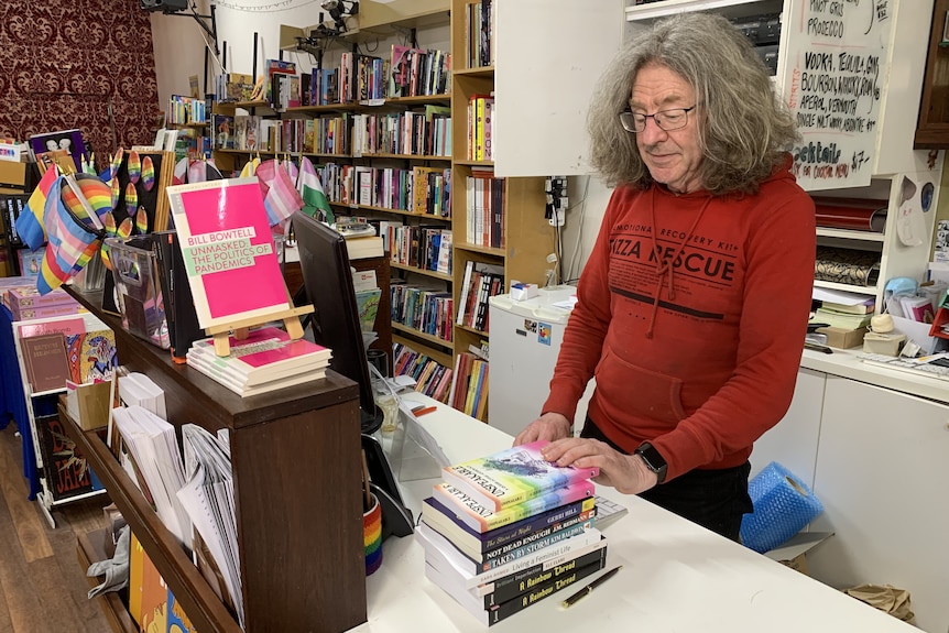 A man standing at the register of a bookstore.