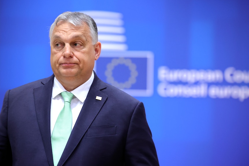 Hungary's Prime Minister Viktor Orban stands in front of a EU Commission sign.