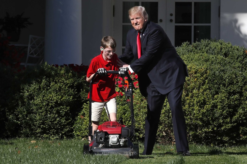 President Donald Trump encourages Frank Giaccio, 11, as he mows the lawn in the Rose Garden