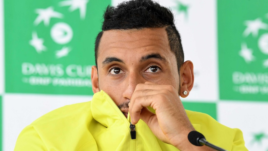 Nick Kyrgios covers his mouth with his shirt